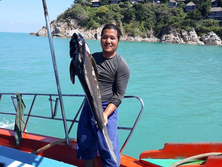 Man on boat holds large fish in the Gulf of Thailand