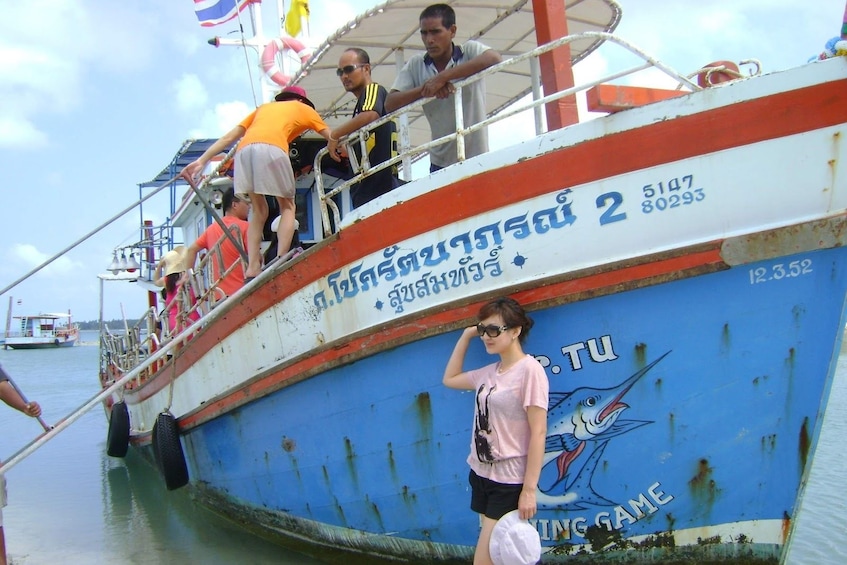 Woman poses in front of large fishing boat in Thailand