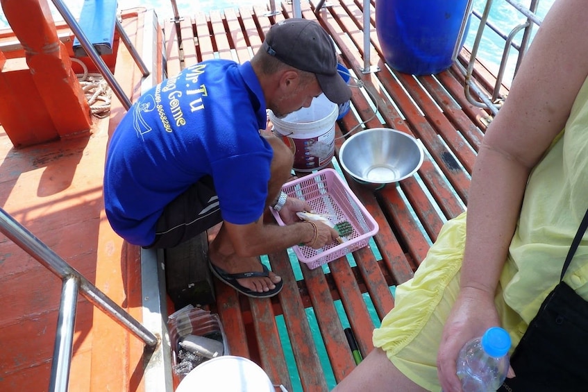 Man skins small fish on boat in the Gulf of Thailand