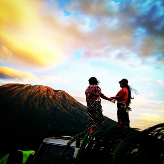 Two people stand on top of a Jeep in Bali