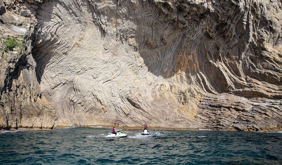 Two people ski near rock face of Mallorca