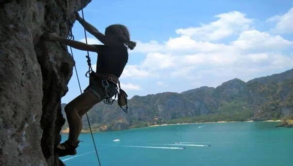 Woman rock climbing over the water in Krabi, Thailand