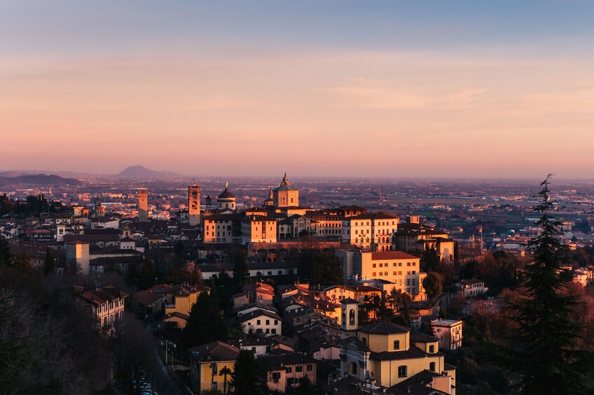 Milan skyline at sunset. Large panoramic view of Milano city, Italy. The  mountain range of the Lombardy Alps in the background. Italian landscape.  Stock Photo