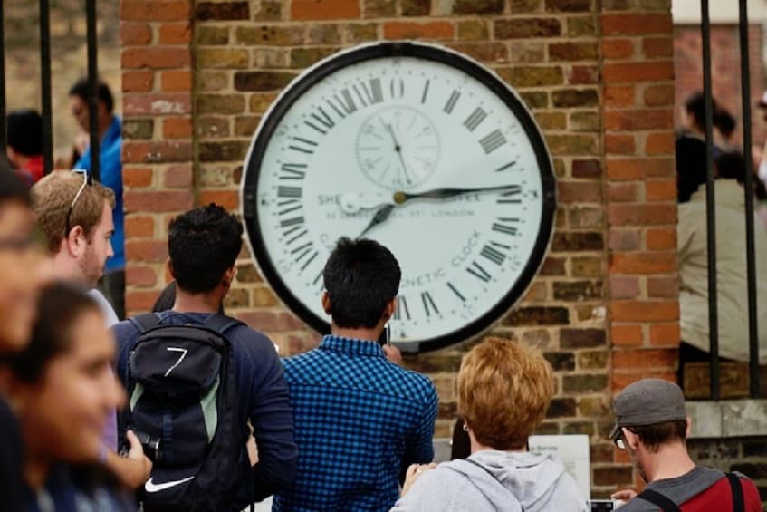 Visitors in front of The Shepherd gate clock at the Royal Observatory in Greenwich, London, England