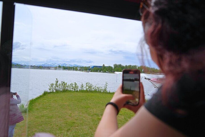 guest taking photo of plane landing on water from inside trolley