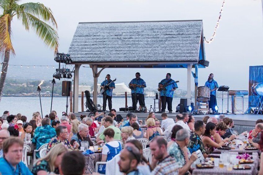 While having dinner with a sea view, visitors listen to traditional Hawaiian music at Island Breeze Luau.