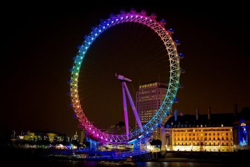 See the London Eye illuminated by night.