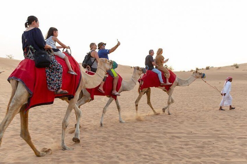 Travelers ride camels through the desert near Dubai.