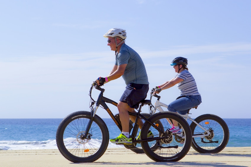 Couple bike along beach in Los Cabos