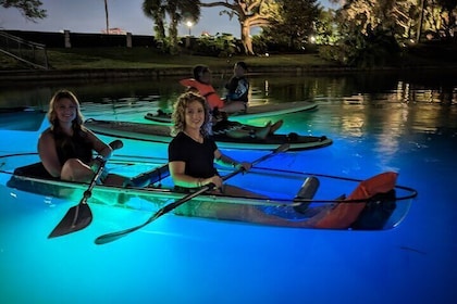 Im Dunkeln leuchtendes klares Kajak oder klares Paddleboard im Paradies