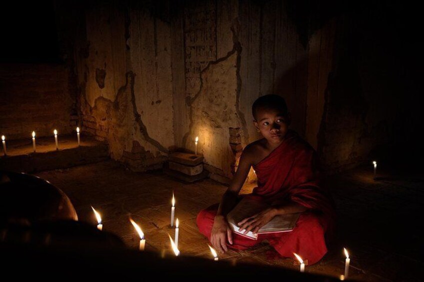 Novice monk reading by candlelight