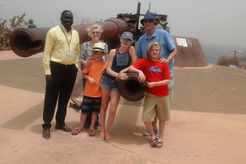 Posing for a picture at the tip of the island with a big cannon in the backgroung