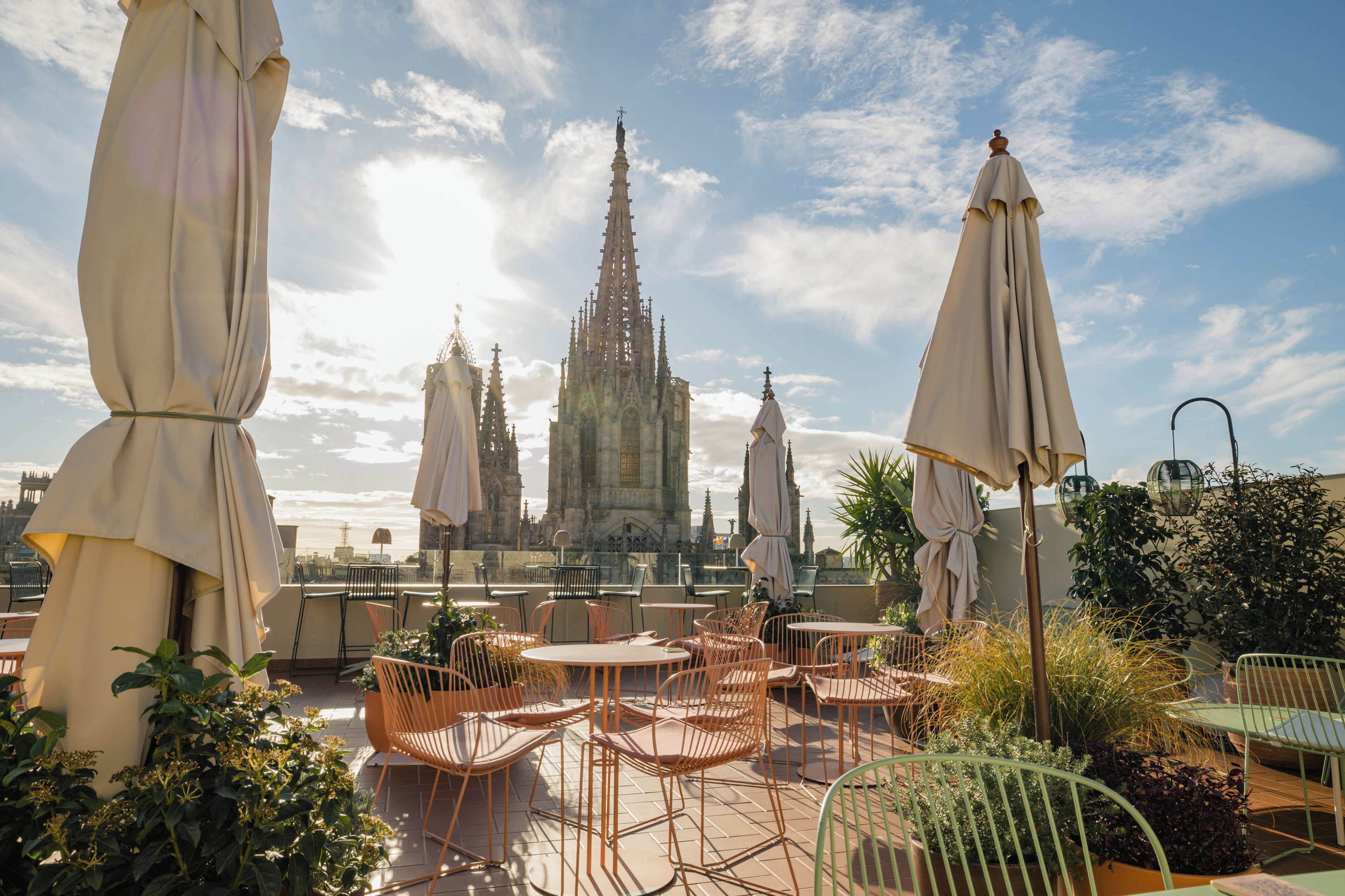 A Gothic cathedral with multiple spires, surrounded by urban buildings and a clear sky.