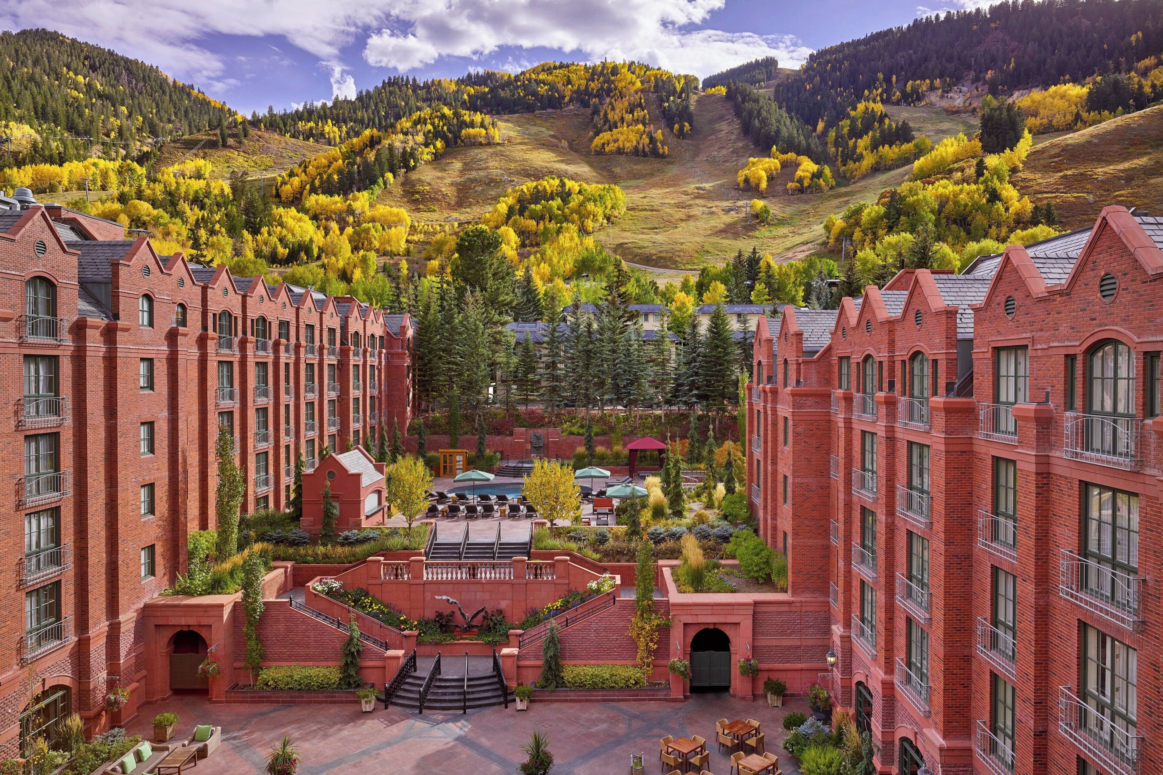 A large, multi-story hotel with a prominent central tower, surrounded by snow-covered trees and a mountainous backdrop.