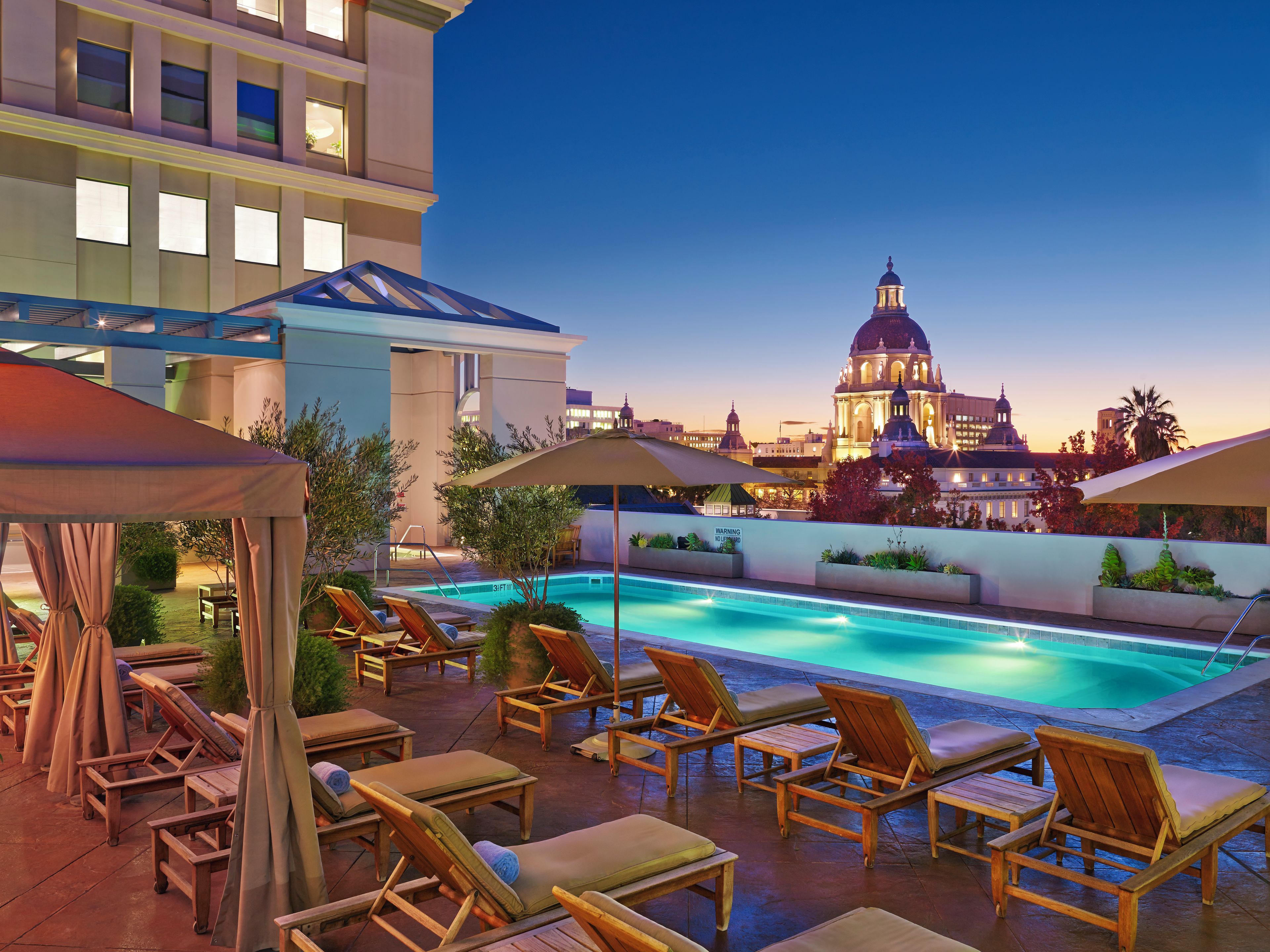 A hotel with a central courtyard featuring a water fountain, palm trees, and a well-lit entrance.