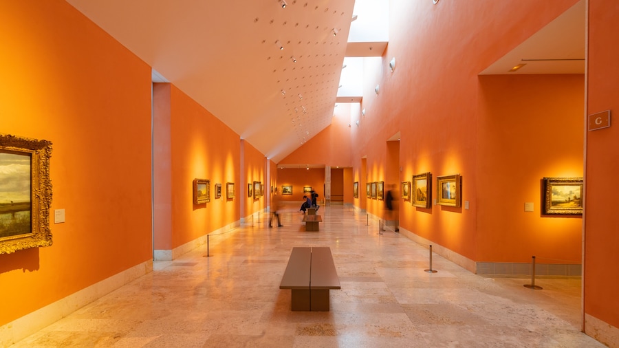 Art gallery hall at the Thyssen-Bornemisza National Museum in Madrid, featuring classic paintings on warm orange walls.