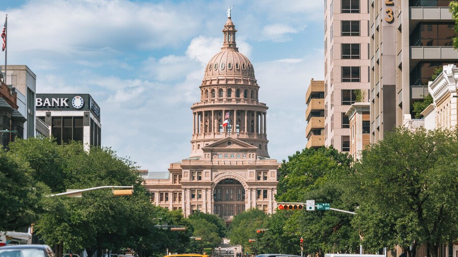 Texas State Capitol with pink granite dome surrounded by trees and buildings in Austin, Texas.