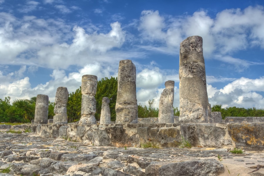 Ancient Mayan ruins surrounded by lush greenery at El Rey Archaeological Zone in Cancun.