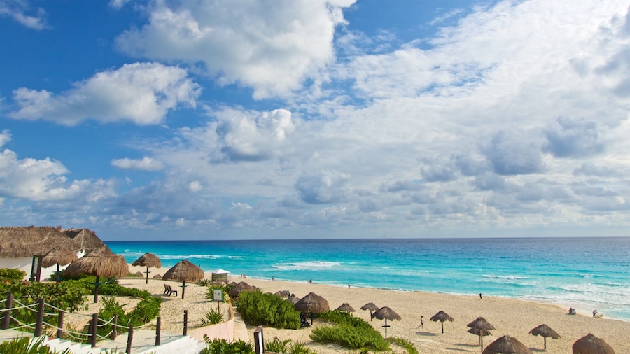 Playa Delfines beach with turquoise waters, white sand, and shaded palapas in Cancun, Mexico.